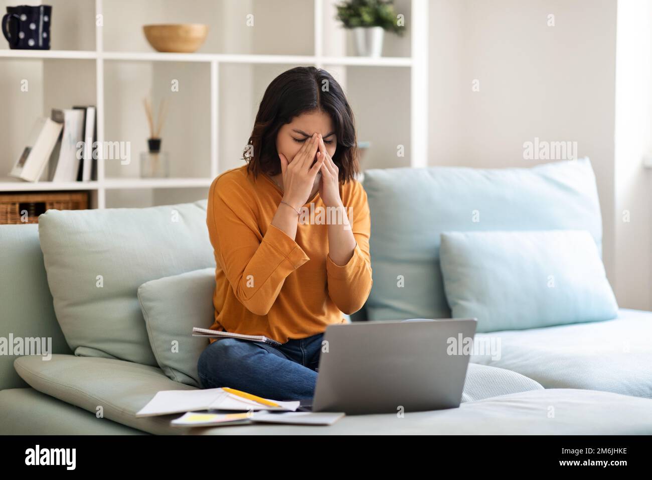 Gestresste Junge Arabische Frau, Die Sich Müde Fühlt, Während Sie Zu Hause Mit Einem Laptop Lernt Stockfoto