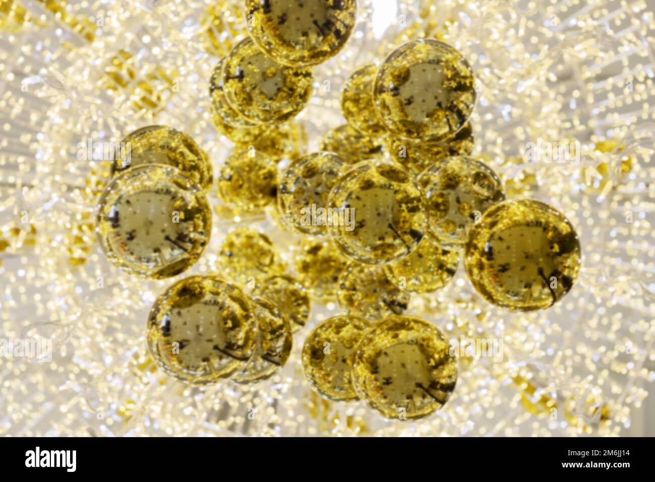 Komposition aus golden glänzenden Weihnachtskugeln auf dem Hintergrund leuchtender Girlanden. Unschärfes Bild. Festliche Postkarte Stockfoto