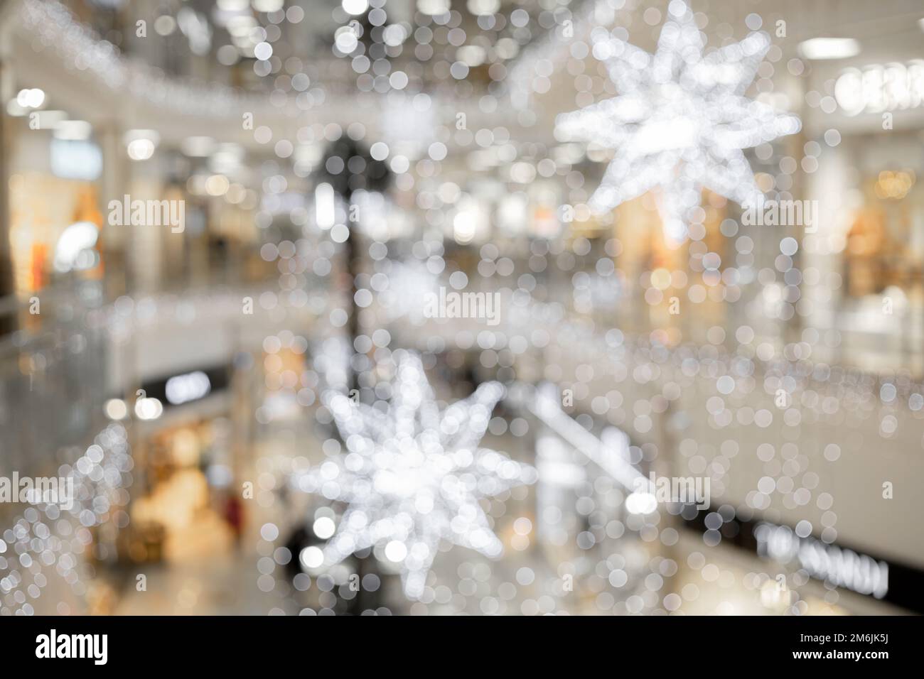 Helle Weihnachtssterne und Girlanden sind in Form von Bokeh im Inneren des Festsaals verschwommen. Unschärfe-Effekt Stockfoto
