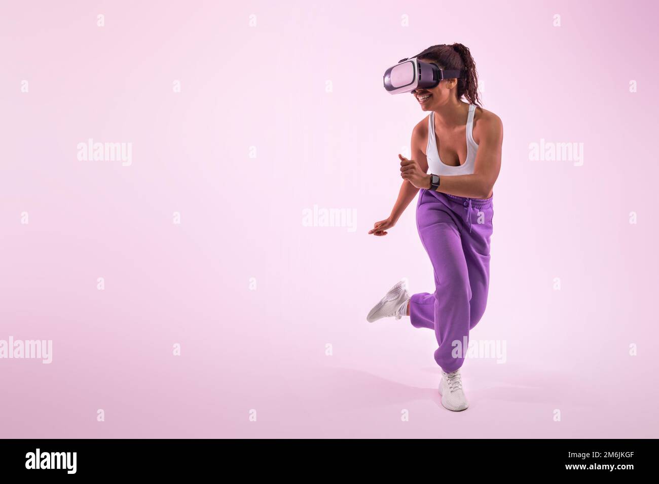Das Metaversum erleben. afroamerikanerin mit Virtual-Reality-Brille, rosa Hintergrund, freier Platz Stockfoto