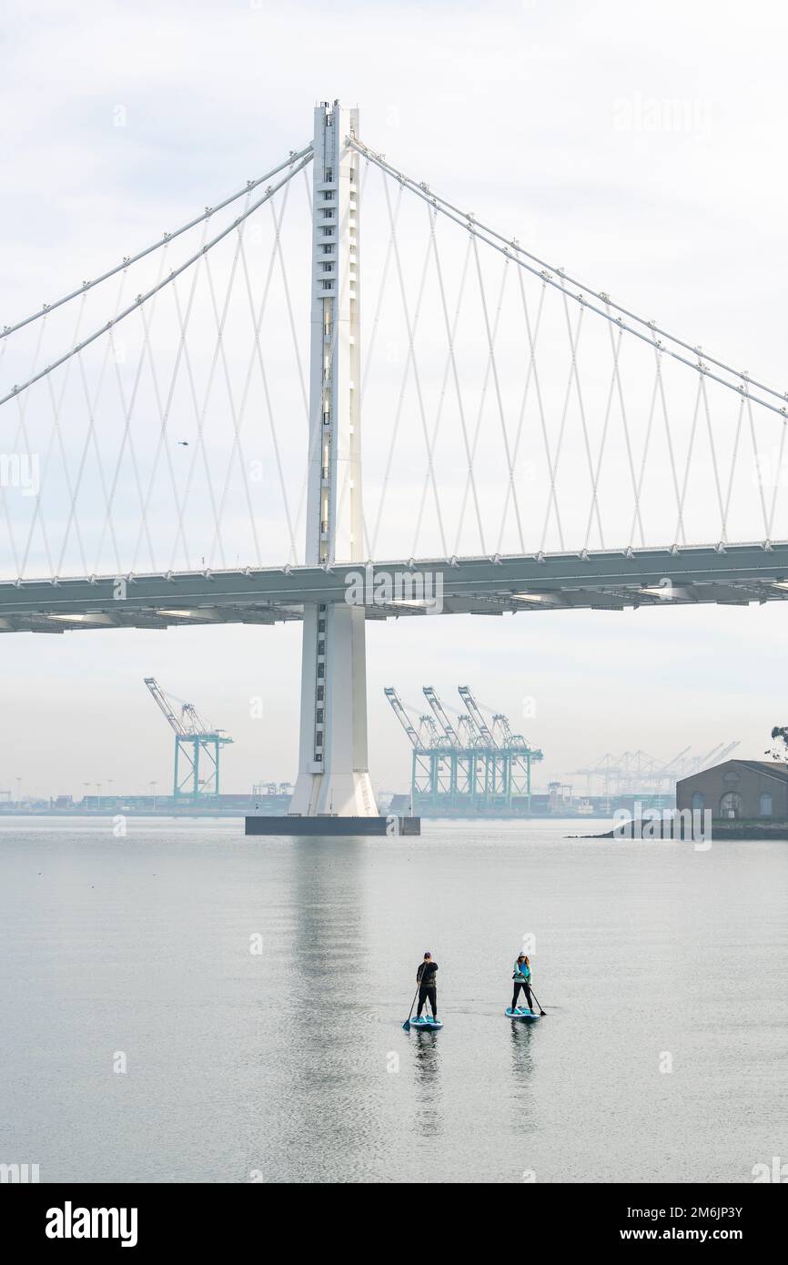 Mann und Frau paddeln in Richtung Oakland Bay Bridge Stockfoto