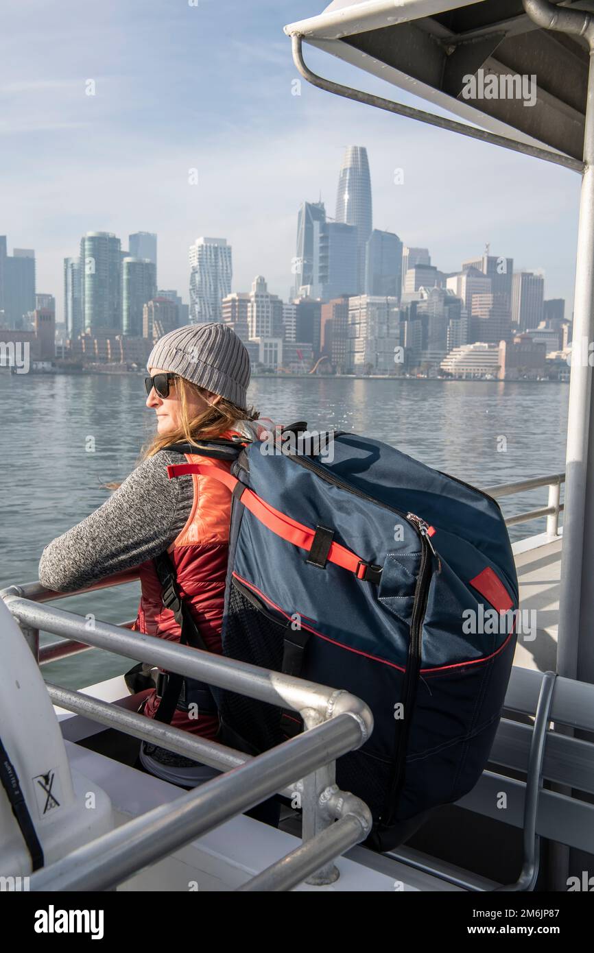 Frau mit Tasche, die sich auf dem Geländer anlehnt, während sie auf dem Schiff reist Stockfoto