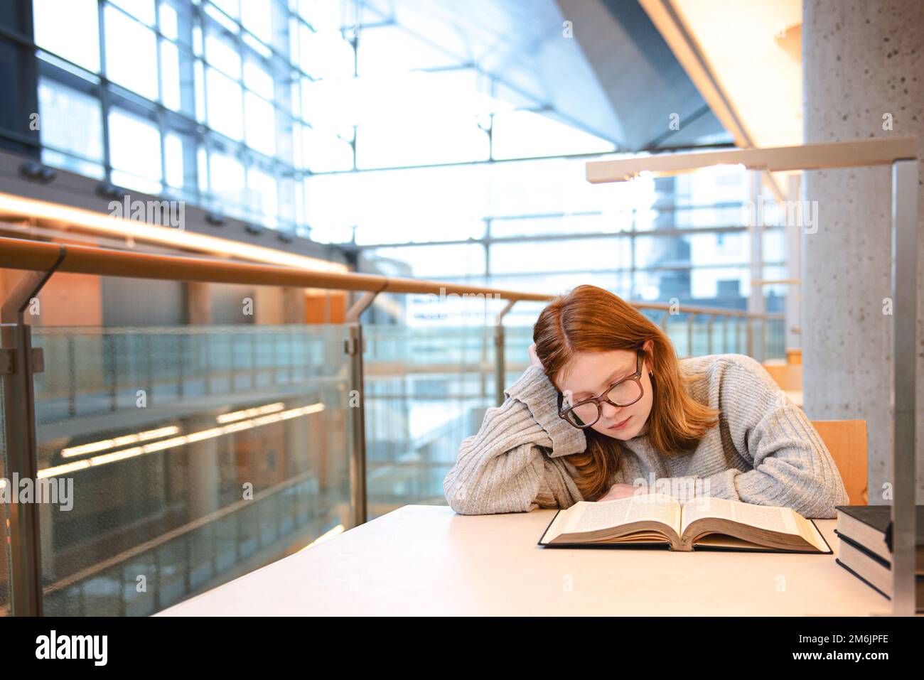 Teenager mit roten Haaren, die in einer städtischen Bibliothek studiert. Stockfoto