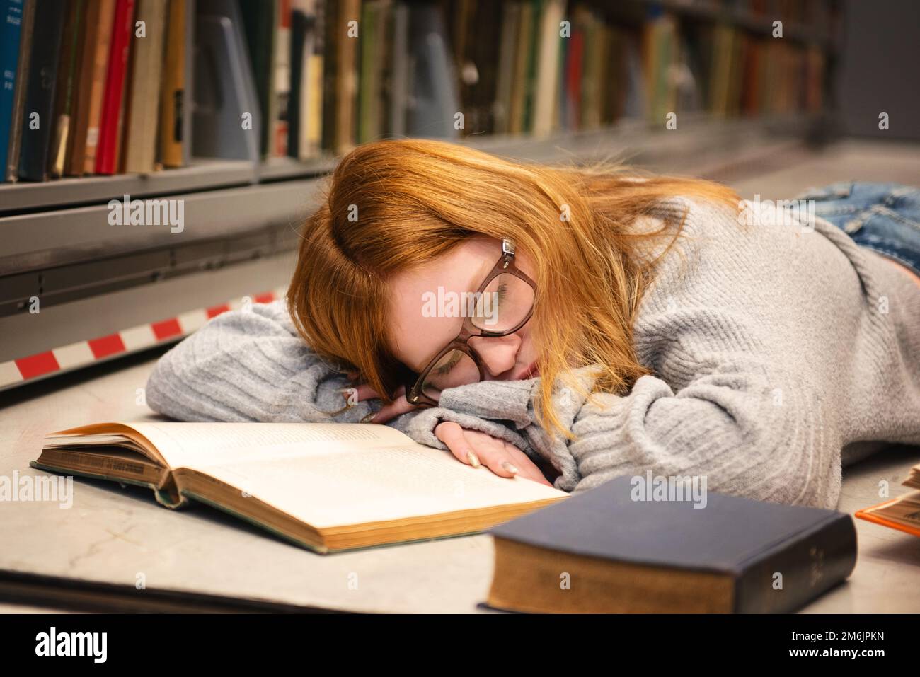 Teenager mit roten Haaren und Brille, die beim Lernen schläft. Stockfoto