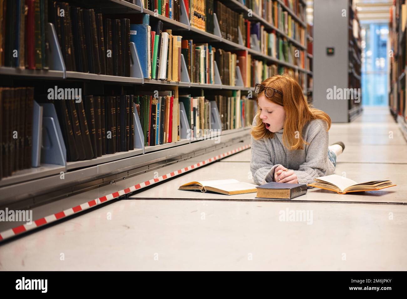 Ein müdes Teenager, das in der Bibliothek lernt. Stockfoto