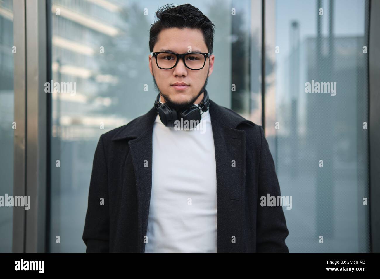 Ein asiatischer Geschäftsmann mit Kopfhörern, mitten im Bild, draußen Stockfoto