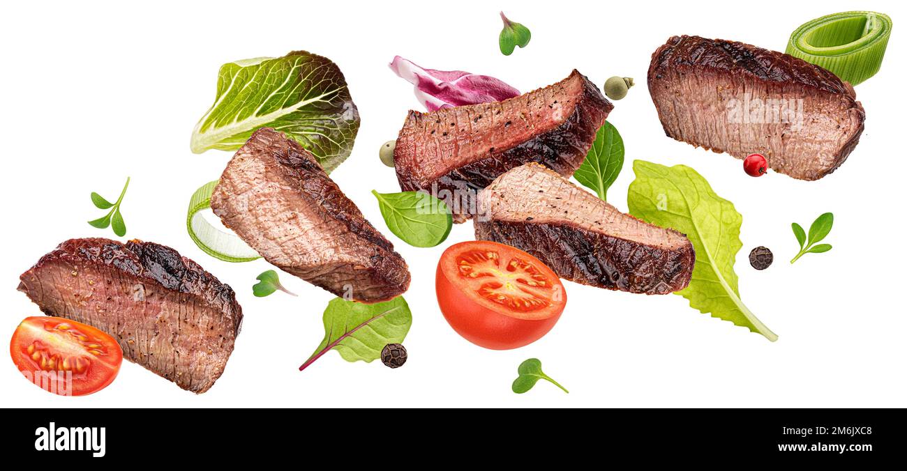 Inhaltsstoffe von fallendem Steak-Salat isoliert auf weißem Hintergrund Stockfoto