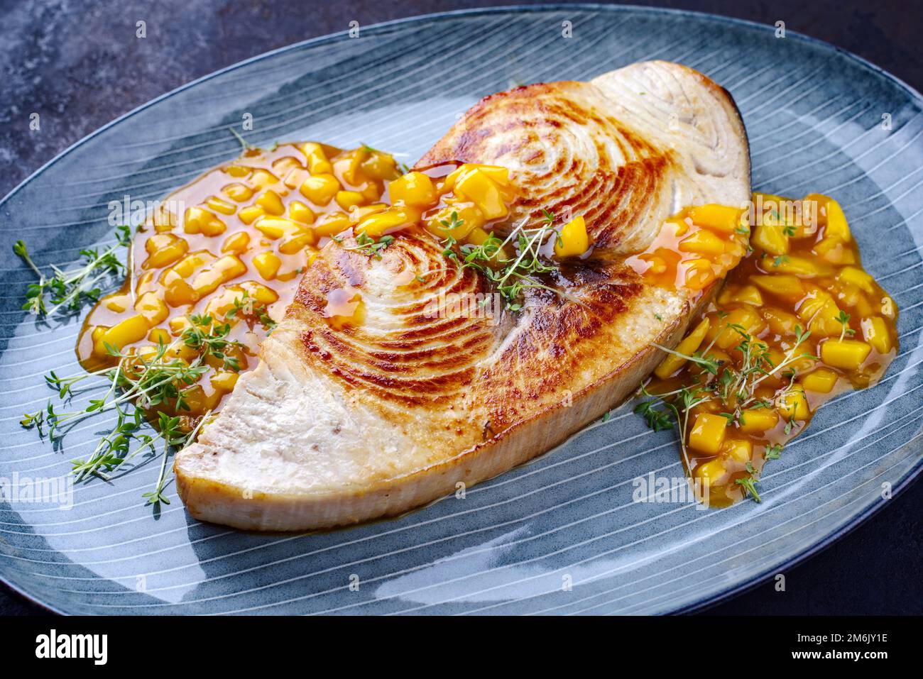 Gebratenes Schwertfischsteak mit Mango-Chutney und Kräutern, serviert aus nächster Nähe auf einer Platte im nordischen Design Stockfoto