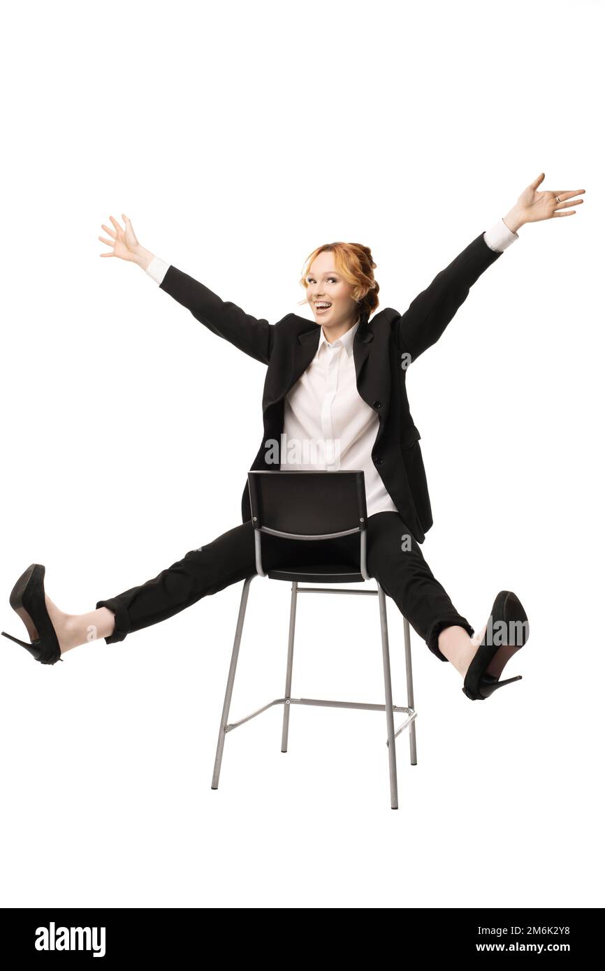 Entzückende junge Geschäftsfrau, die mit Händen und Beinen auf einem Stuhl sitzt Stockfoto