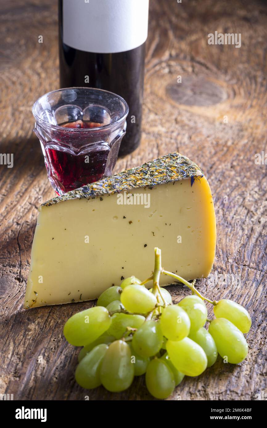 Bergkäse mit Trauben auf Holz Stockfoto