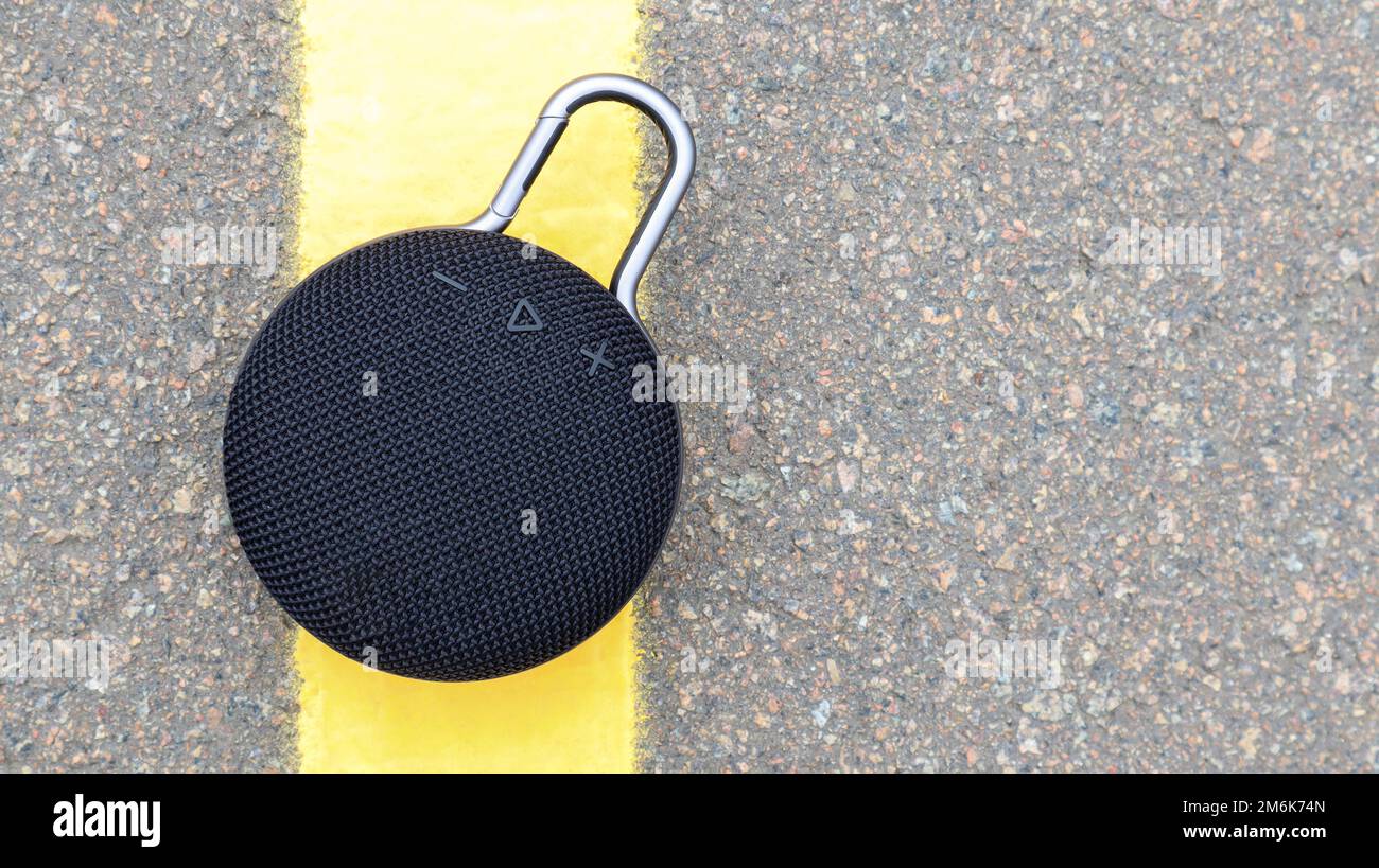 Wasserdichter runder Bluetooth-Lautsprecher mit Karabiner in Schwarz. Digitales Musik- und Audiokonzept. Mini, für Reisen geeignet. Stockfoto