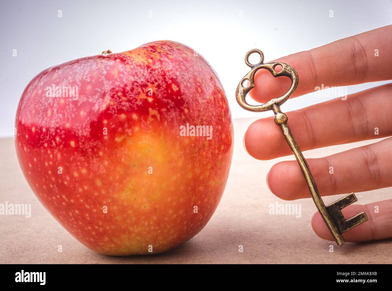 Eine Hand, die einen Schlüssel neben einem Apfel hält Stockfoto