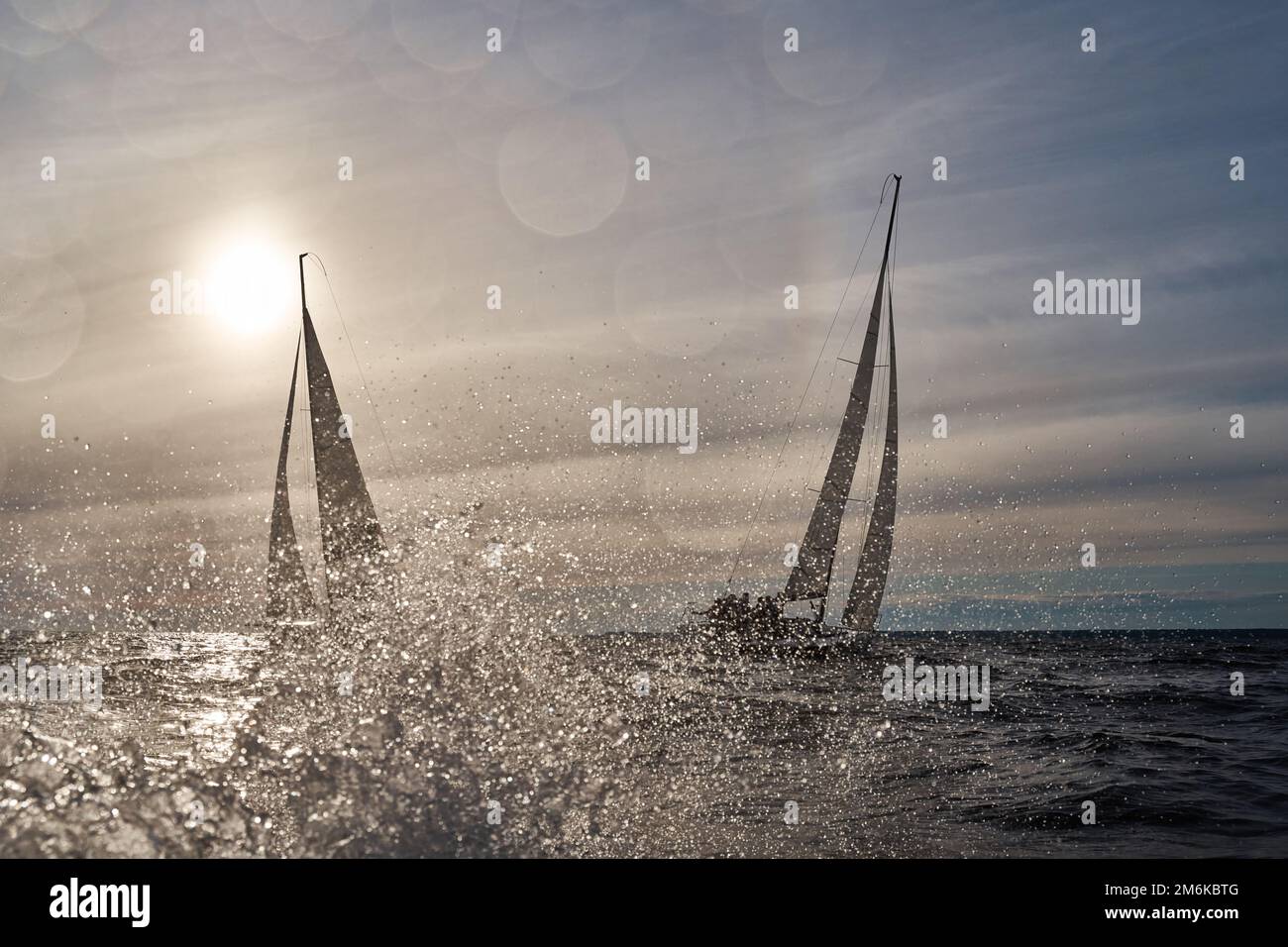 Segelyachten in Regatta bei Sonnenuntergang, Segelregatta, Heißjagd, Wasserspritzer, der klare Himmel Stockfoto