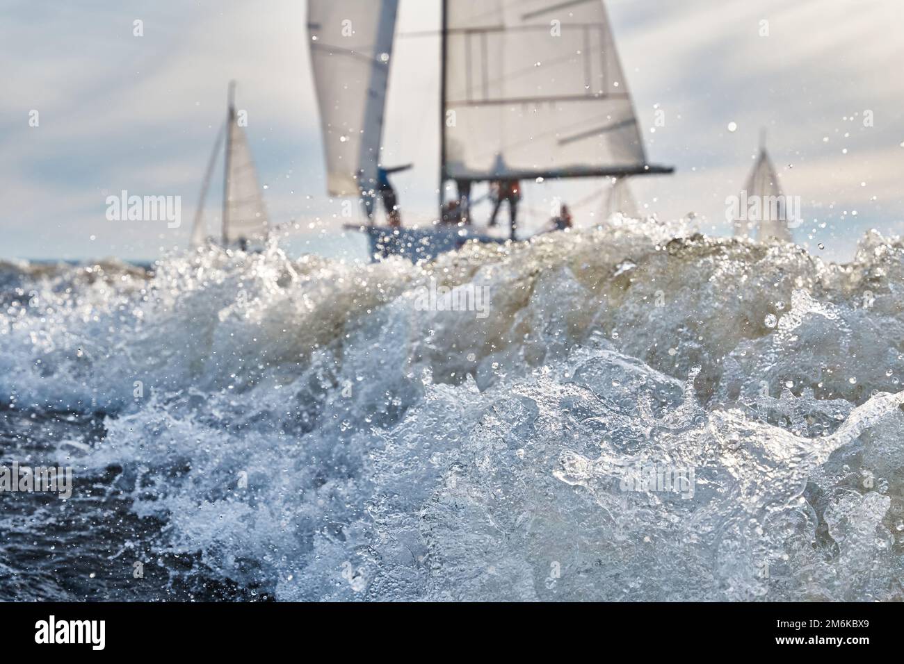 Segelyachten in Regatta bei Sonnenuntergang, Segelregatta, Heißjagd, Wasserspritzer, der klare Himmel Stockfoto