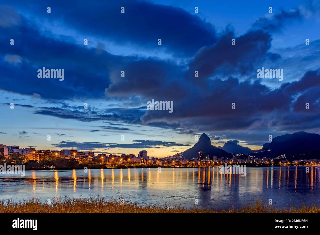 Abenddämmerung in der Lagune Rodrigo de Freitas mit den Gebäuden, Hügeln und Lichtern der Stadt Stockfoto