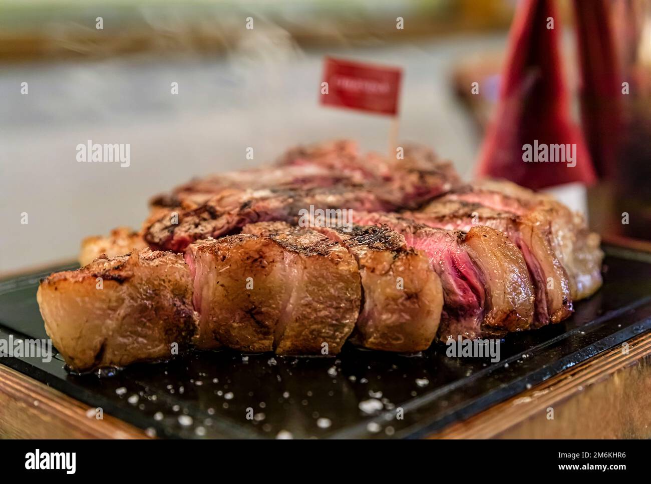 Klassisches gebratenes, trockenes, gereiftes T-Bone Florentiner Steak von einer Chianina-Kuh, die in einem Restaurant in Florenz, Italien, auf einer Servierplatte vom Grill dampft Stockfoto