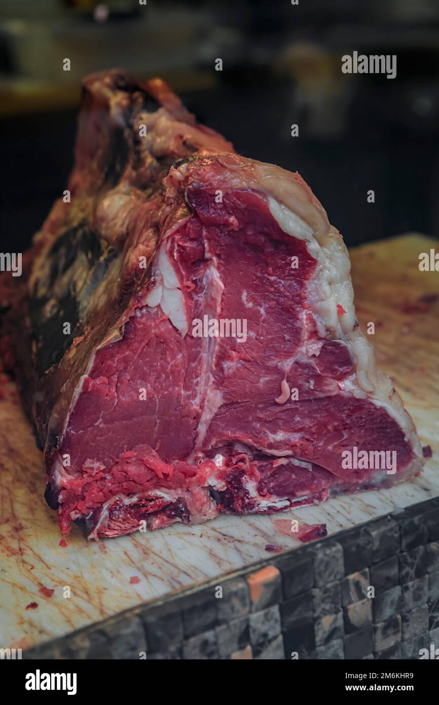 Klassisches ungeschnittenes Stück trockenes, gereiftes T-Bone Florentiner Steak von einer Chianina-Kuh auf einem Metzgertisch in einem Restaurant in Florenz, Italien Stockfoto