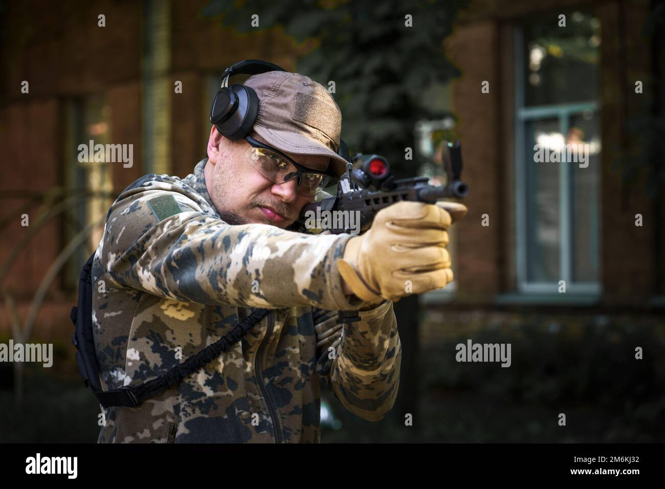 Kadett-Trainingskurs, Mann mit Waffe in Militäruniform, taktisches Gehörschutz-Headset. Ausbildung in Schießoperationen Cent Stockfoto