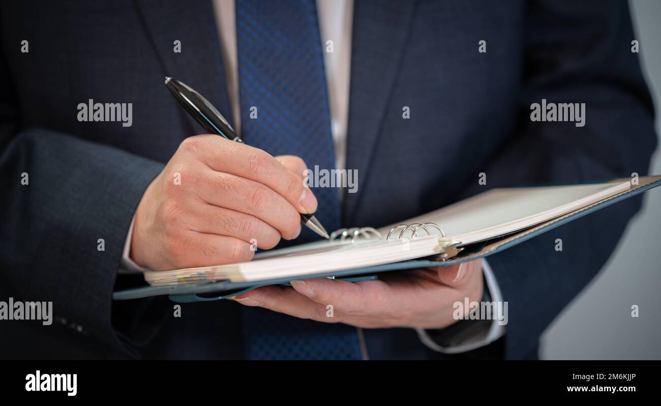 Hände eines Geschäftsmannes, der einen Zeitplan schreibt oder Ideen in ein Tagebuch schreibt Stockfoto