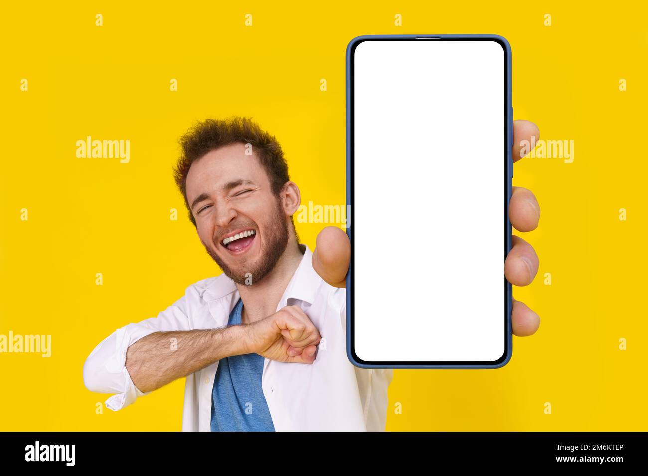 Ja, ein glücklicher, aufgeregter junger Mann mit Smartphone zeigt einen weißen leeren Bildschirm isoliert über gelbes Spiel, Wette, Lotteriegewinn Stockfoto