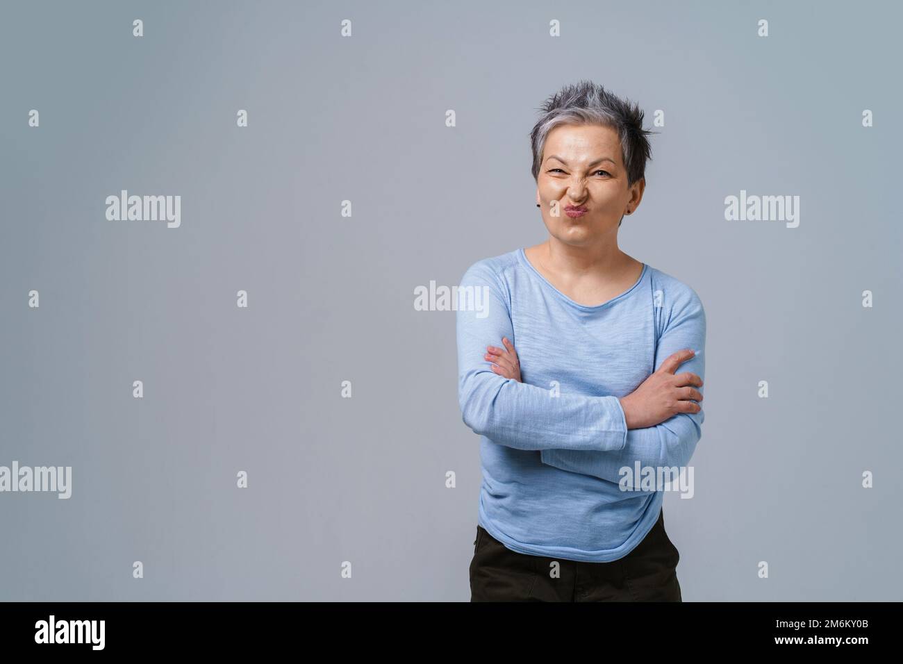 Zeigt positive Abneigung im Gesicht reife Geschäftsfrau mit grauen Haaren in 50s mit gefalteten Händen und Kopierbereich links für PR Stockfoto