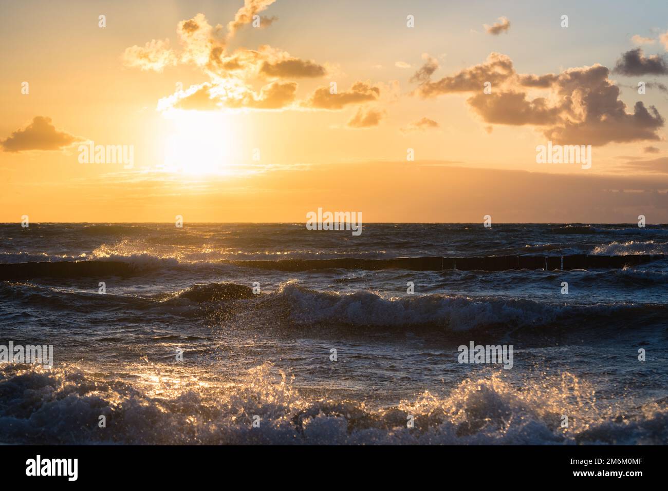 Farbenfroher Sonnenuntergang mit Wolkenbedeckung über dem Sonnenuntergang am Strand - dramatischer Sonnenuntergang auf der ostsee Stockfoto