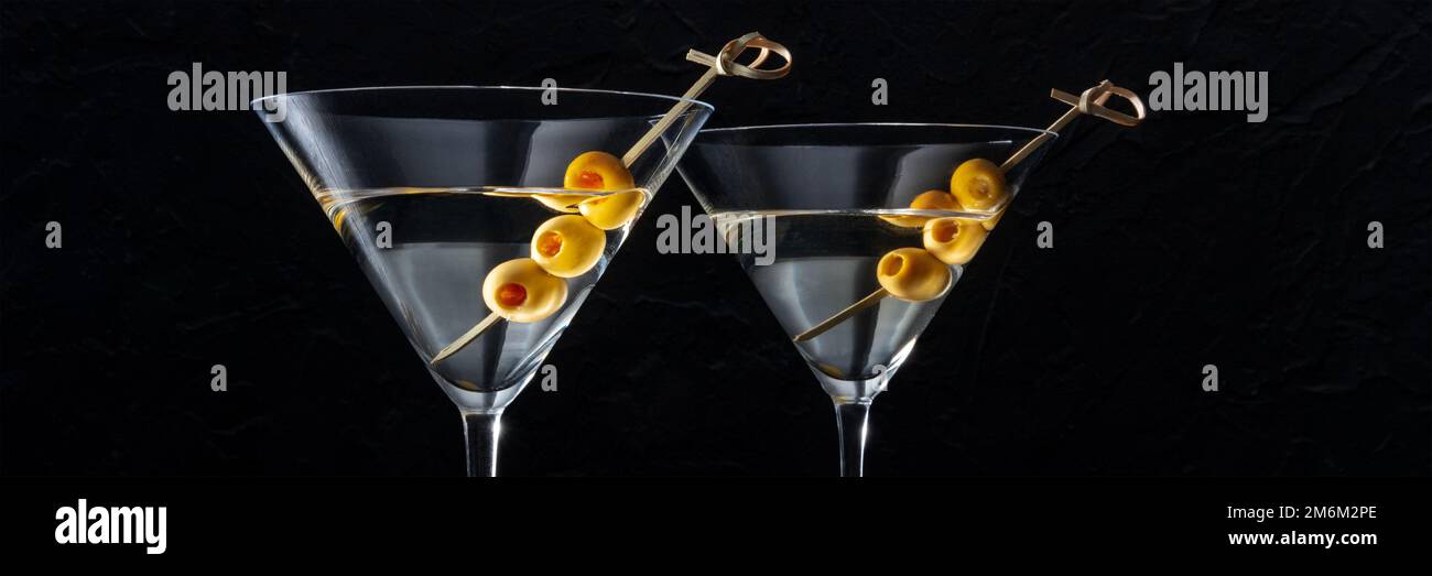 Martini, zwei Gläser mit scharfem Oliven-Panorama, auf schwarzem Hintergrund Stockfoto