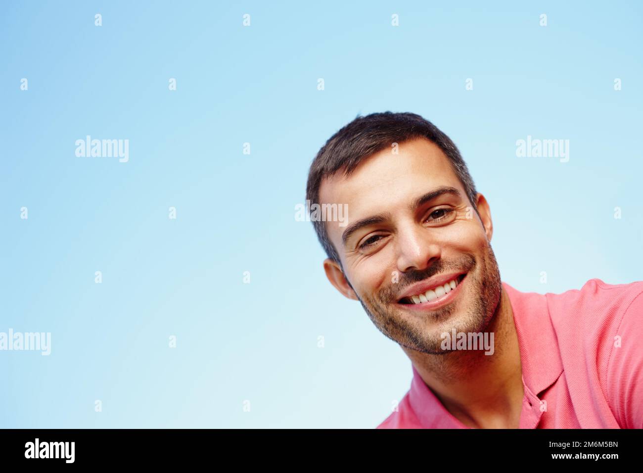 Hey, da unten. Ein kleines Porträt eines gutaussehenden jungen Mannes vor einem blauen Himmel. Stockfoto