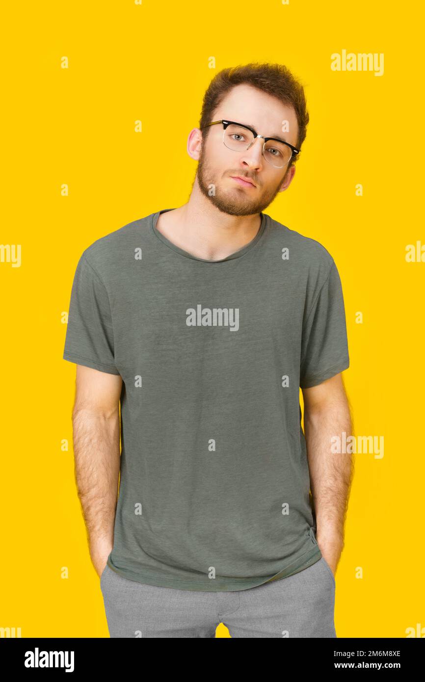 Attraktiver junger Mann in Freizeitkleidung und Brille mit gelbem Hintergrund. Stilvoller Bart elegant lässiger Look Hipster man. Th Stockfoto