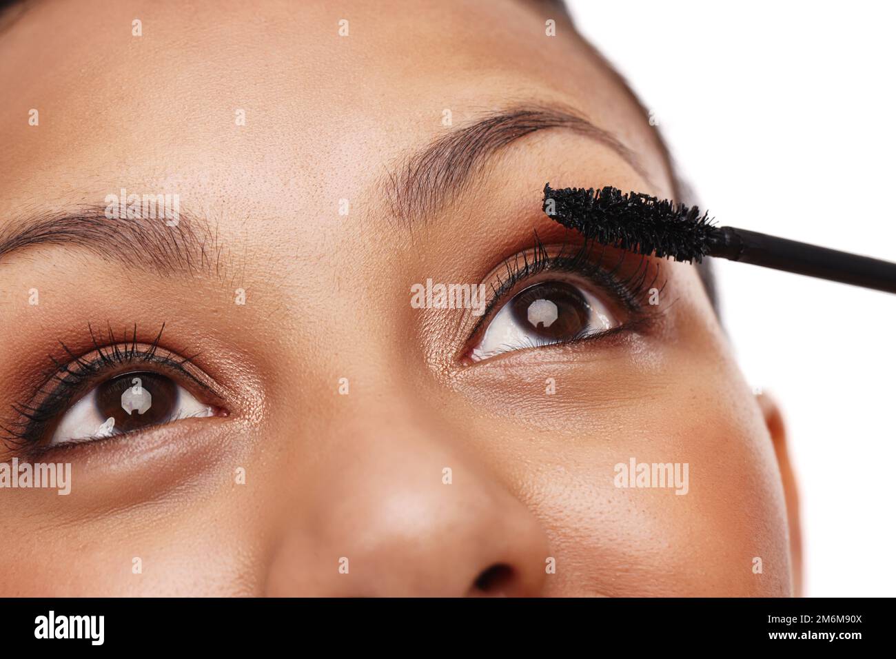 Ein Meisterwerk entwerfen. Eine wunderschöne junge Frau, die in einem Studio Mascara aufträgt, isoliert auf weiß. Stockfoto