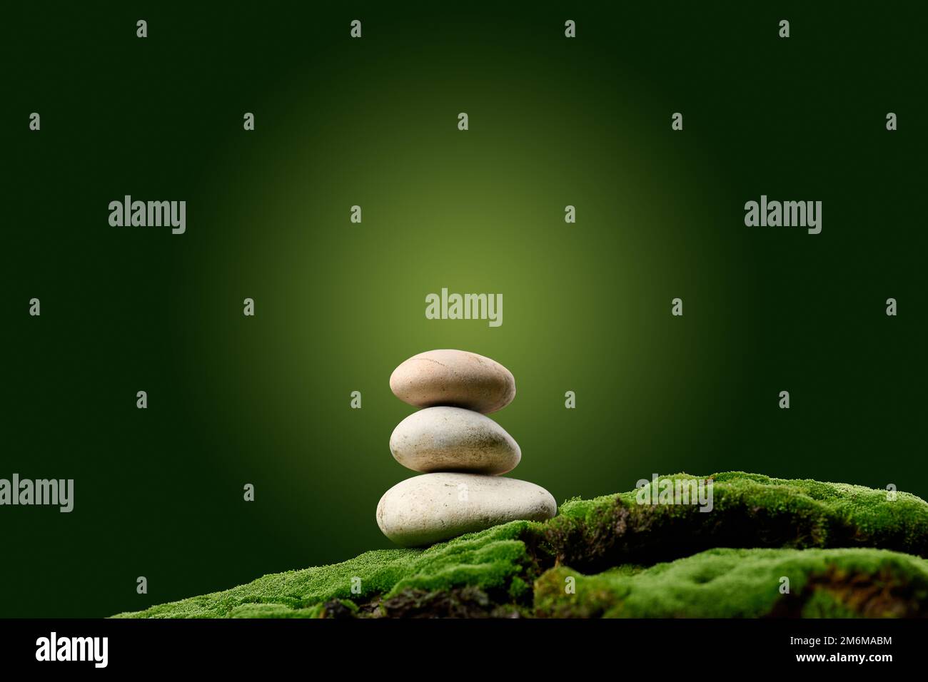 Stapel runder Steine auf grünem Moos, grüner Hintergrund. Podium, um Produkte zu präsentieren Stockfoto