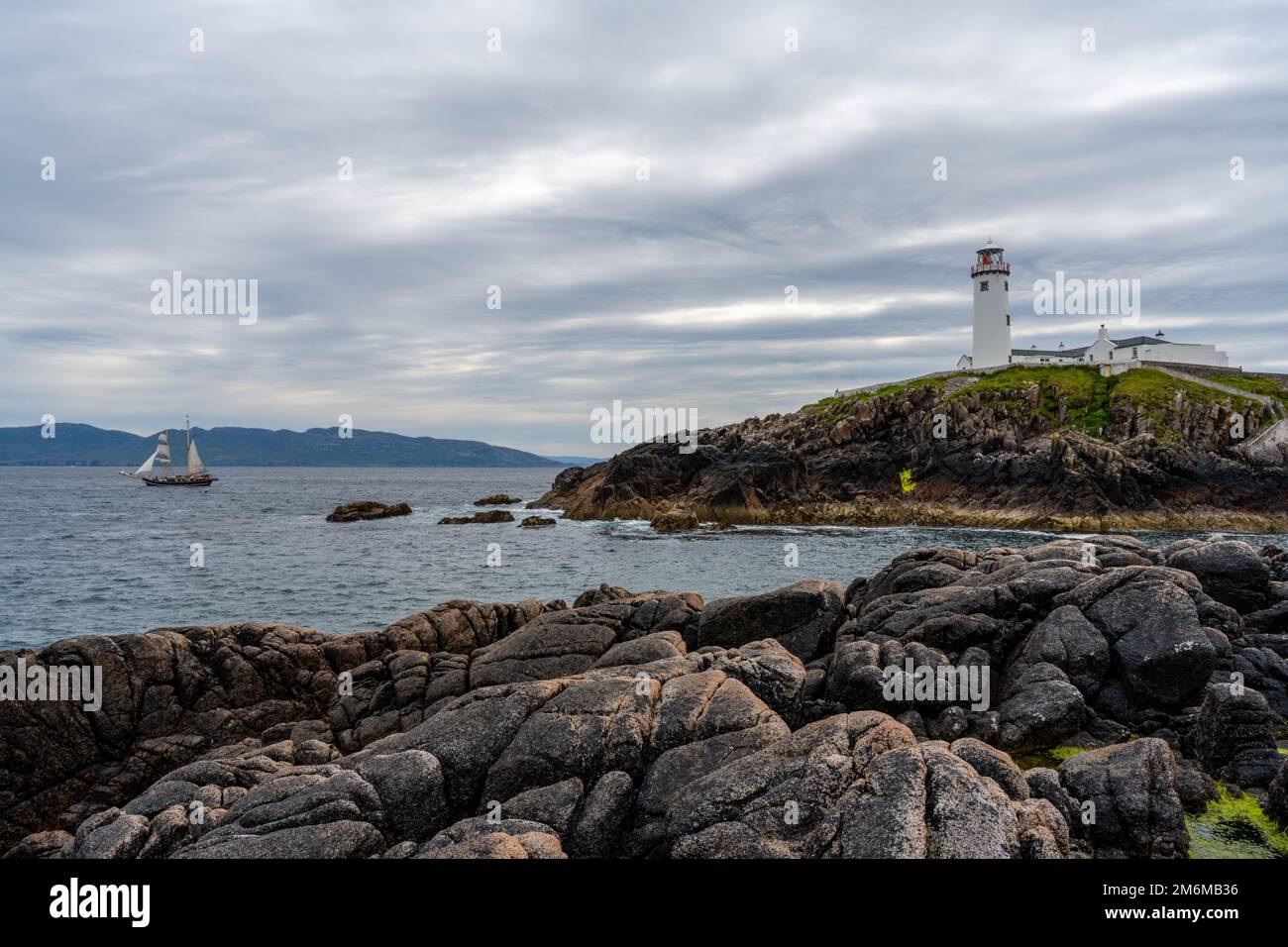 Ein Blick auf den Fanad Head Lighthouse an der Nordküste Irlands mit einem alten zweimagigen Segelboot Stockfoto