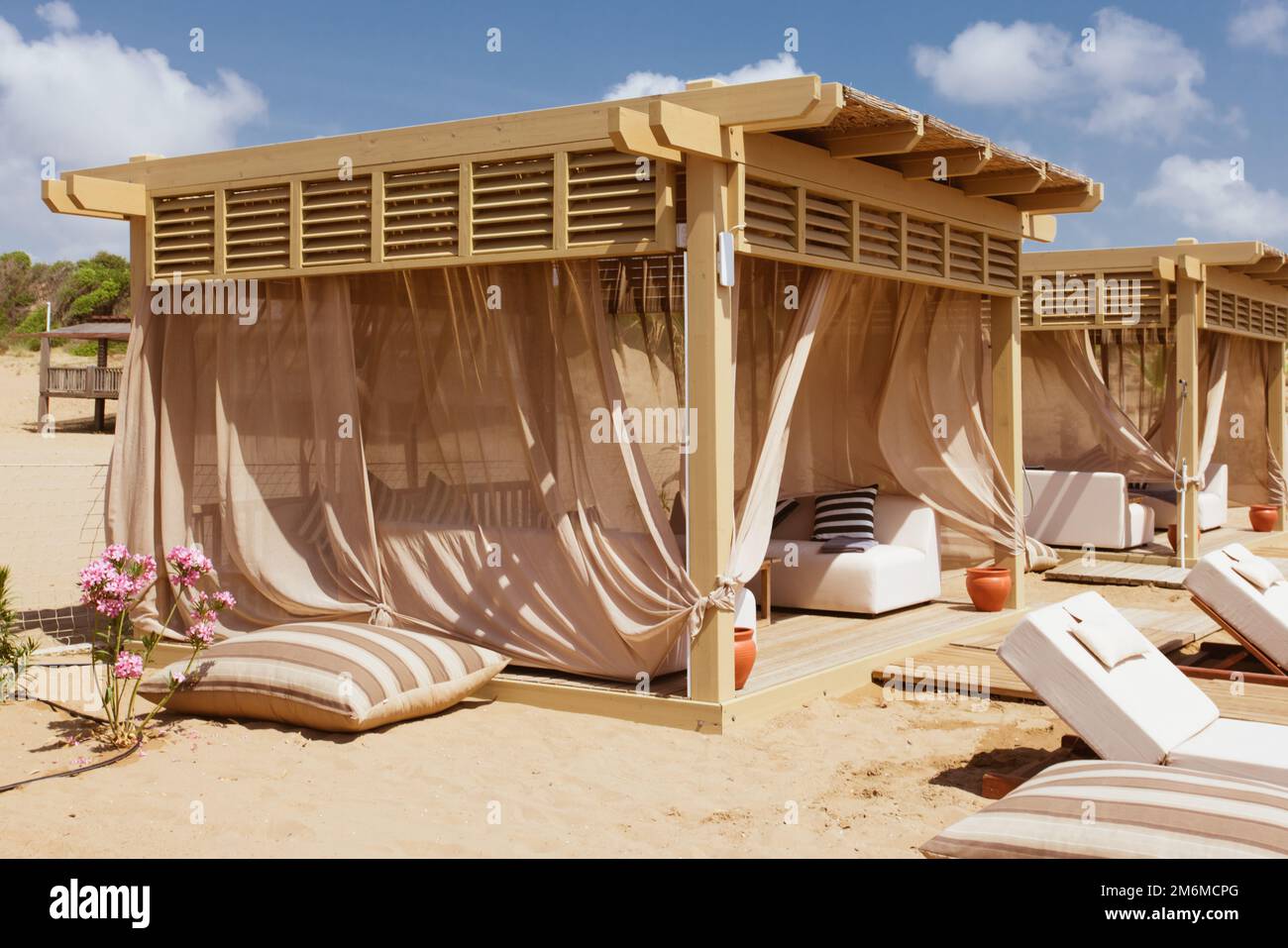 Schöner Lounge-Pavillon zum Entspannen am Strand mit Blick auf Sand und tropische Bäume und blauem Himmel. Luxuriöser Sommerurlaub in t Stockfoto