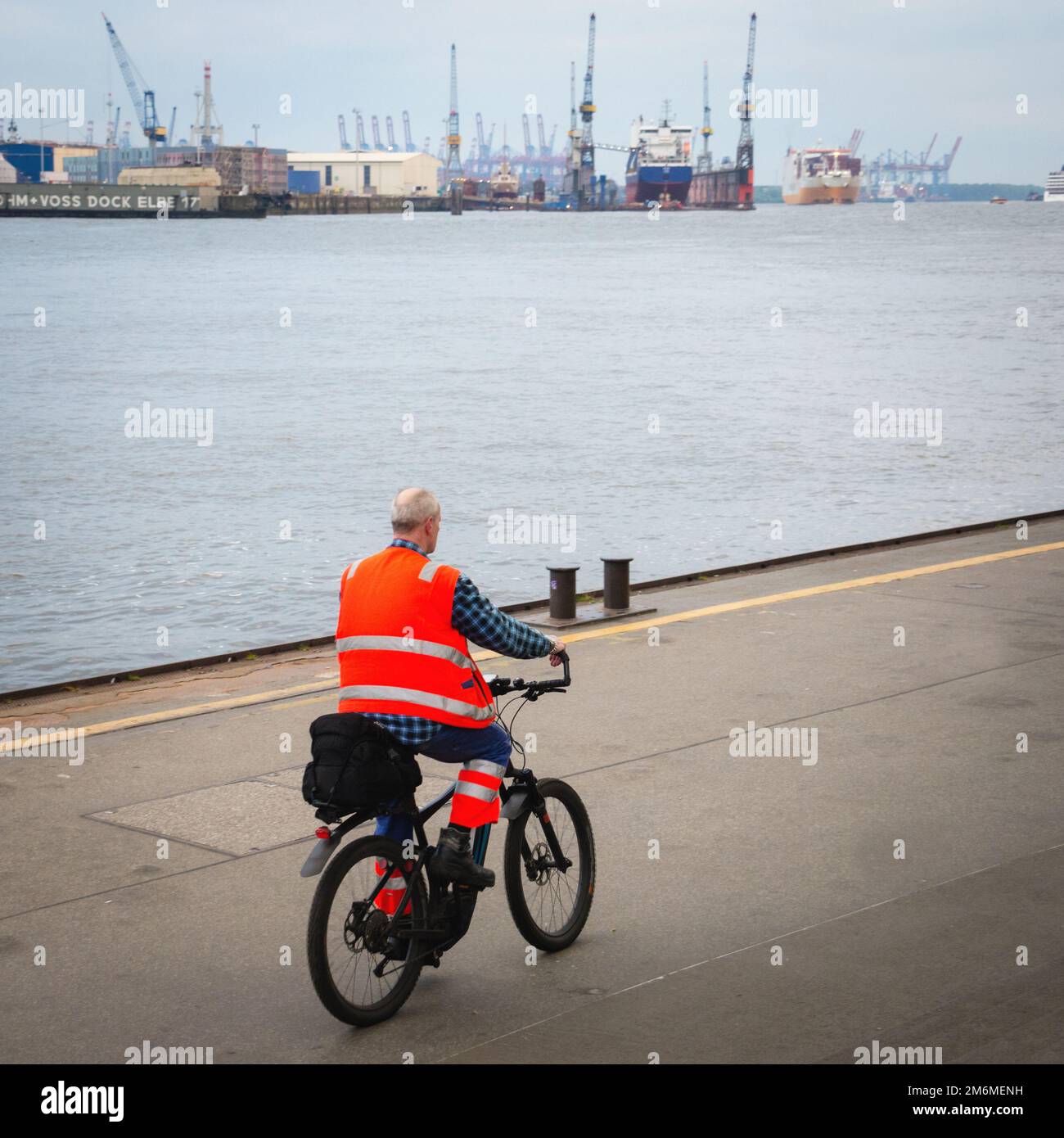 Männlicher Arbeiter mit reflektierender Jacke am kommerziellen Dock Stockfoto