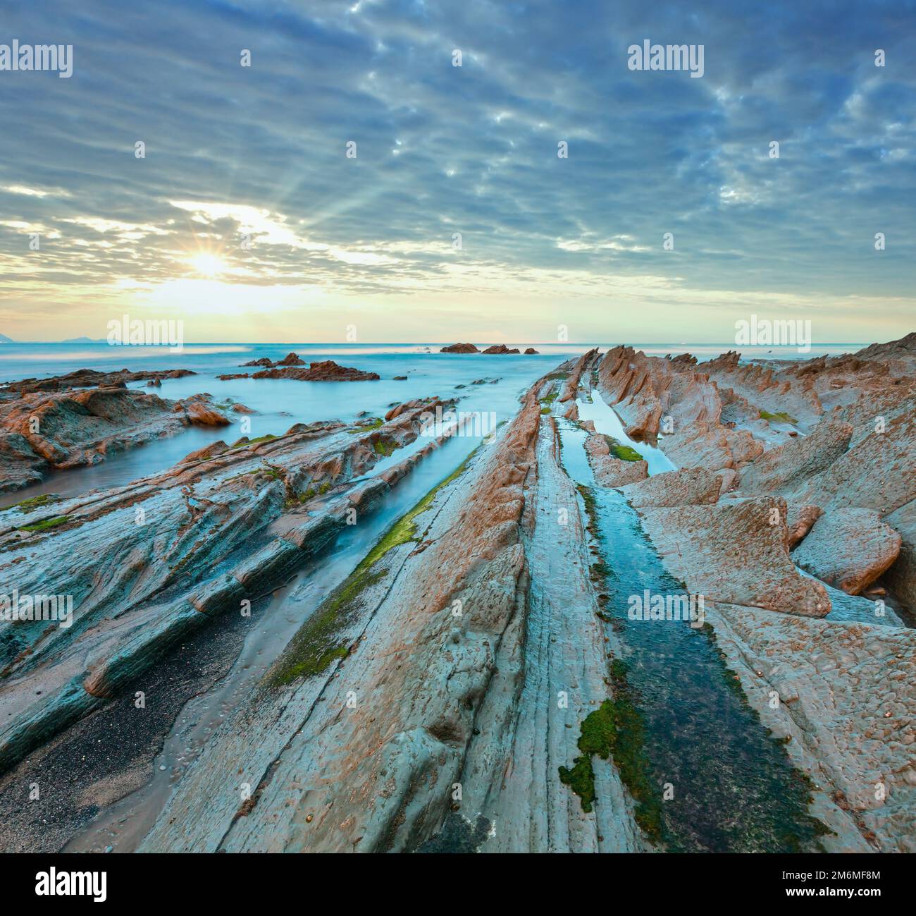 Twilight Ozean Küste mit geripptem stratiform Rock. Stockfoto