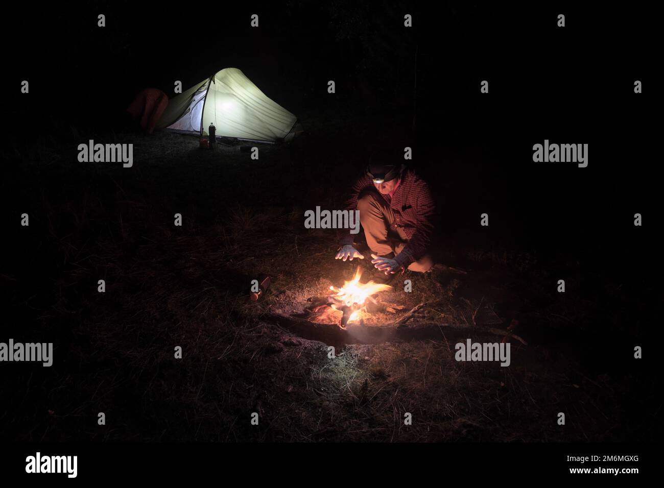 Im Dunkeln wärmt sich ein Mann am Feuer in Sizilien, Ätna Park, Italien Stockfoto