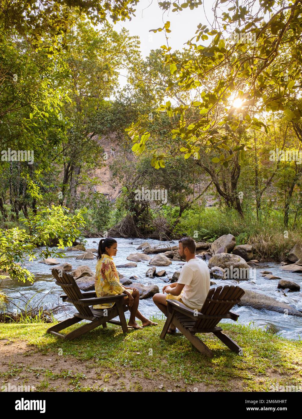 Ein Paar Männer und Frauen, die sich am Fluss im Stuhl entspannen, Camping in der Natur Konzept Stockfoto