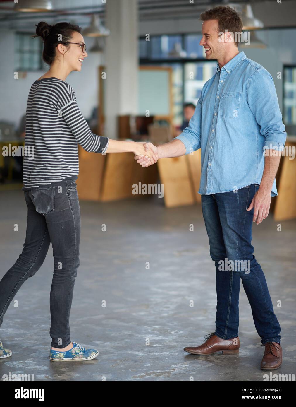 Wir heißen den Neuen willkommen. Männliche und weibliche kreative Profis begrüßen sich gegenseitig mit einem Händedruck. Stockfoto