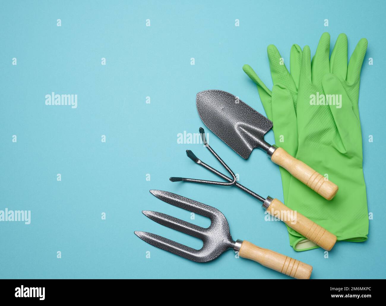 Gartenwerkzeuge zur Beetbearbeitung im Garten und gummierte grüne Handschuhe Stockfoto
