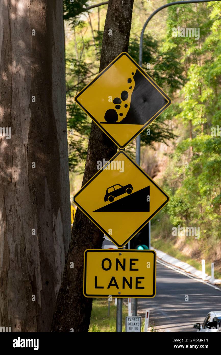 Warnschilder auf dem Ziegenpfad am Tamborine Mountain Australia. Steile, einspurige Straße mit Gefahr von Steinen. Ampelkontrolle. Stockfoto