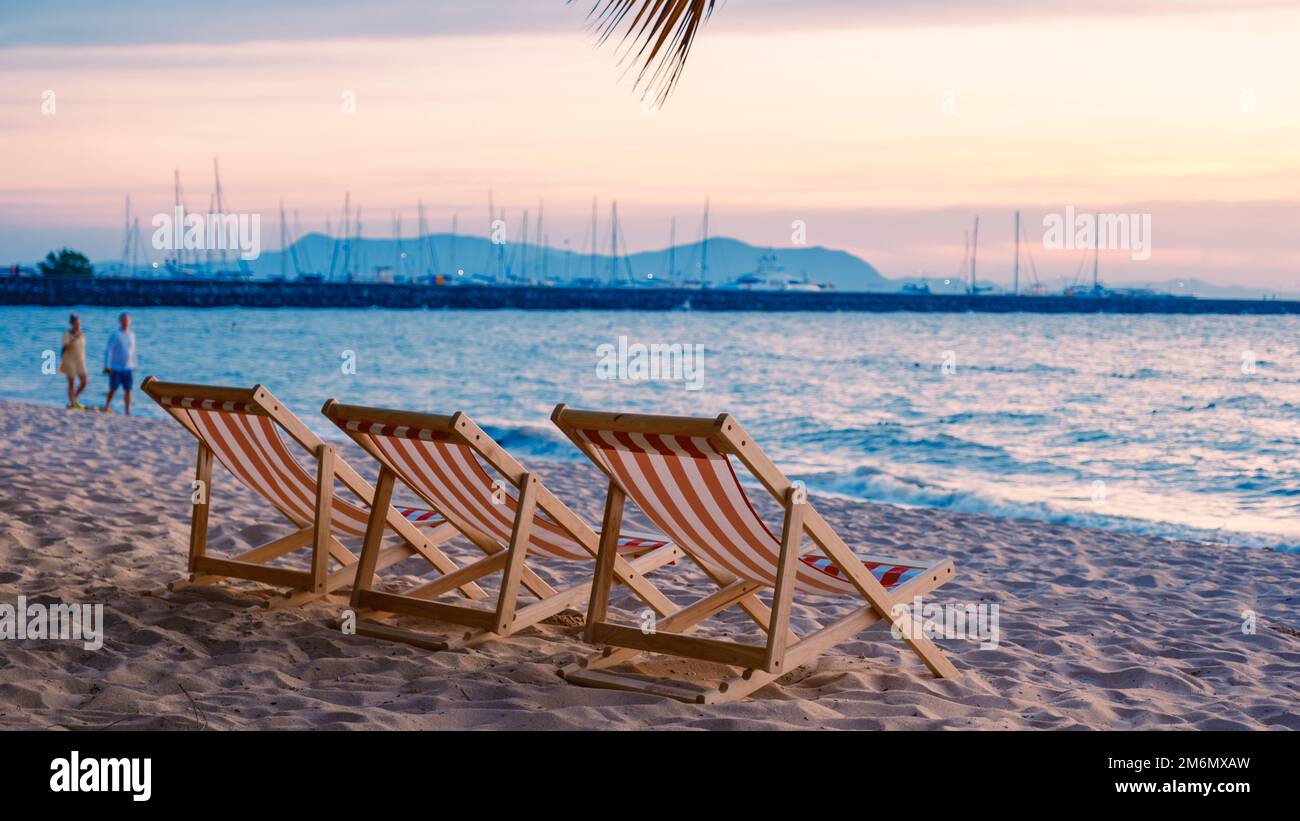 Liegestuhl am Strand mit Palmen bei Sonnenuntergang am Na Jomtien Beach Pattaya Thailand. Stockfoto