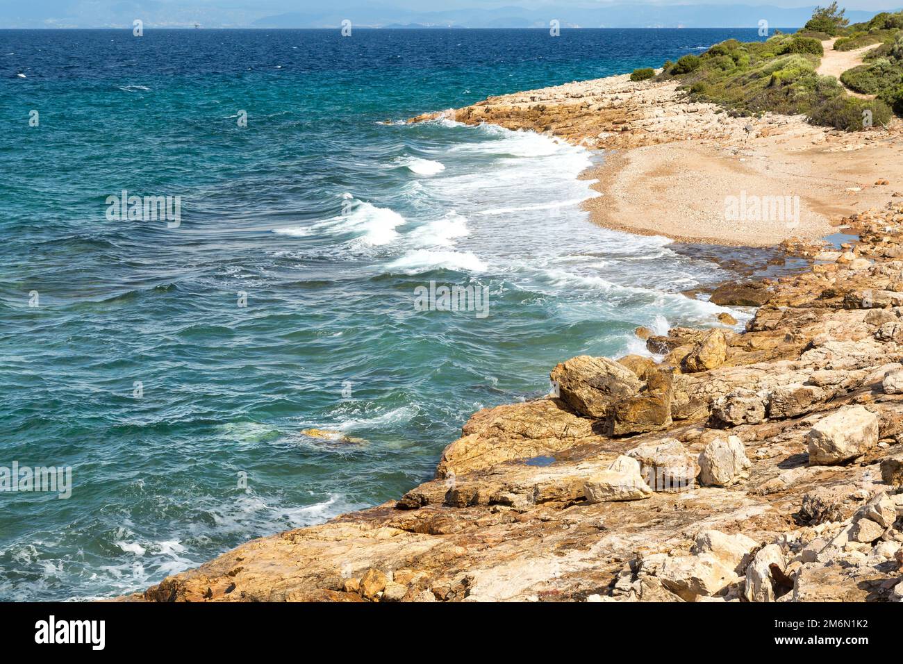 Sommerhintergrund mit Wellen an der steinernen Strandküste Stockfoto