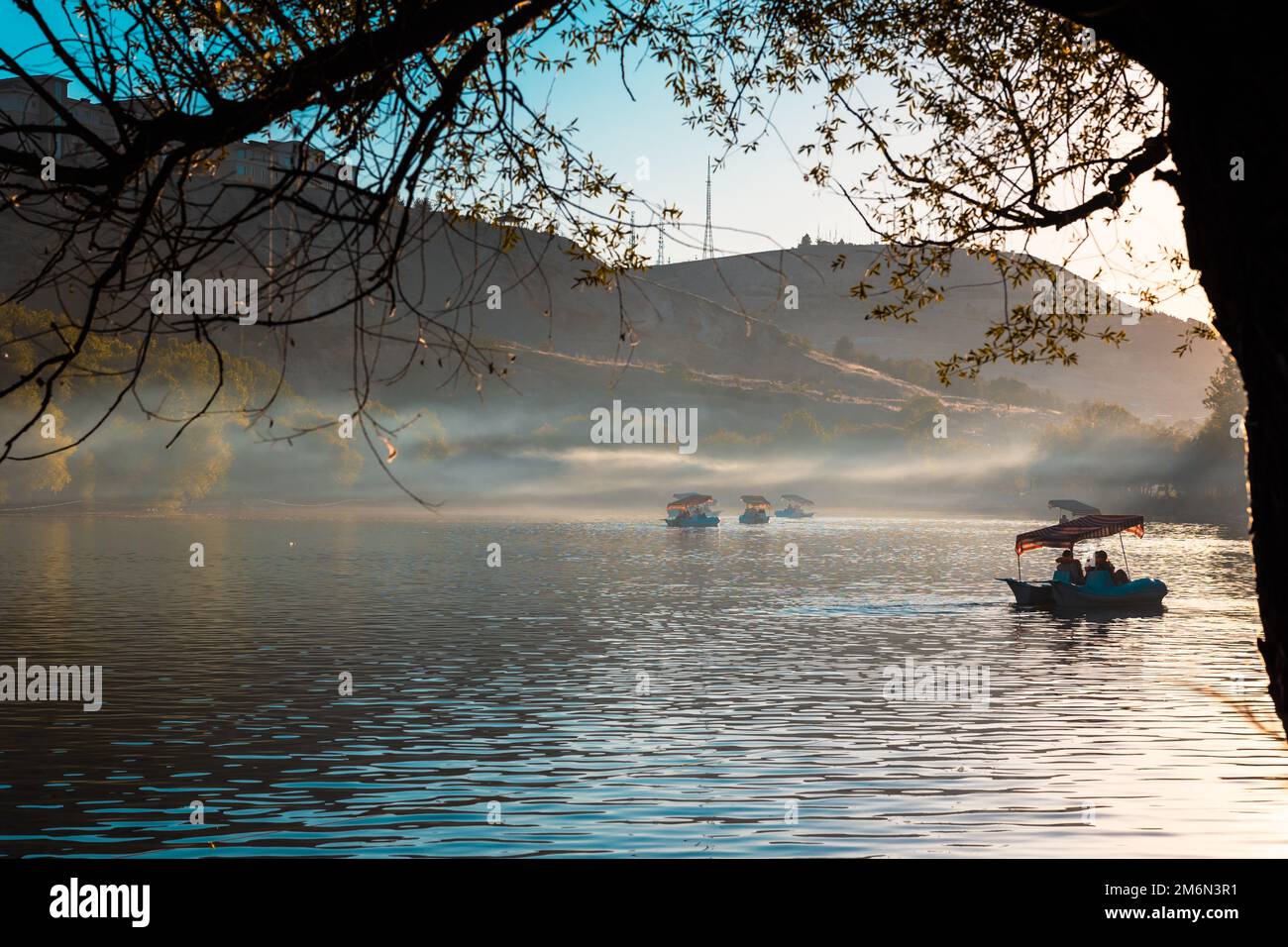 Tretboote auf dem See bei Sonnenuntergang. Konzeptfoto für Reise- oder Wochenendaktivitäten. Dunst oder Nebel auf dem See. Stockfoto