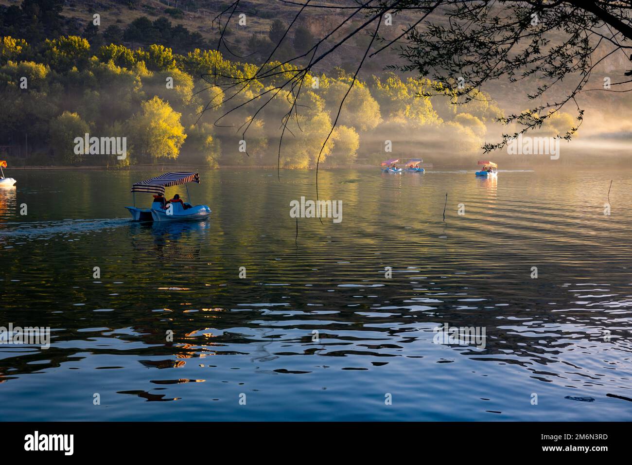 Tretboote oder Tretboote auf dem See bei Sonnenuntergang mit Dunst oder Nebel. Freizeit- oder Wochenendaktivitäten, Konzeptfoto. Stockfoto