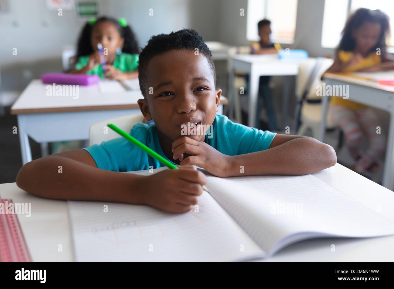 afroamerikanischer Grundschüler, der während des Unterrichts Gesicht macht, während er am Schreibtisch sitzt Stockfoto