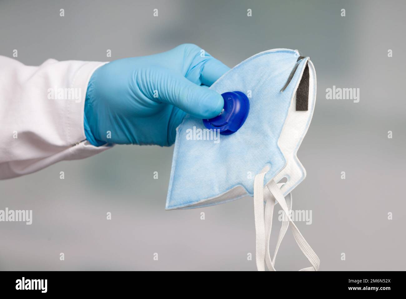 Eine Hand in blauen medizinischen Handschuhen präsentiert eine N95 Gesichtsmaske Stockfoto