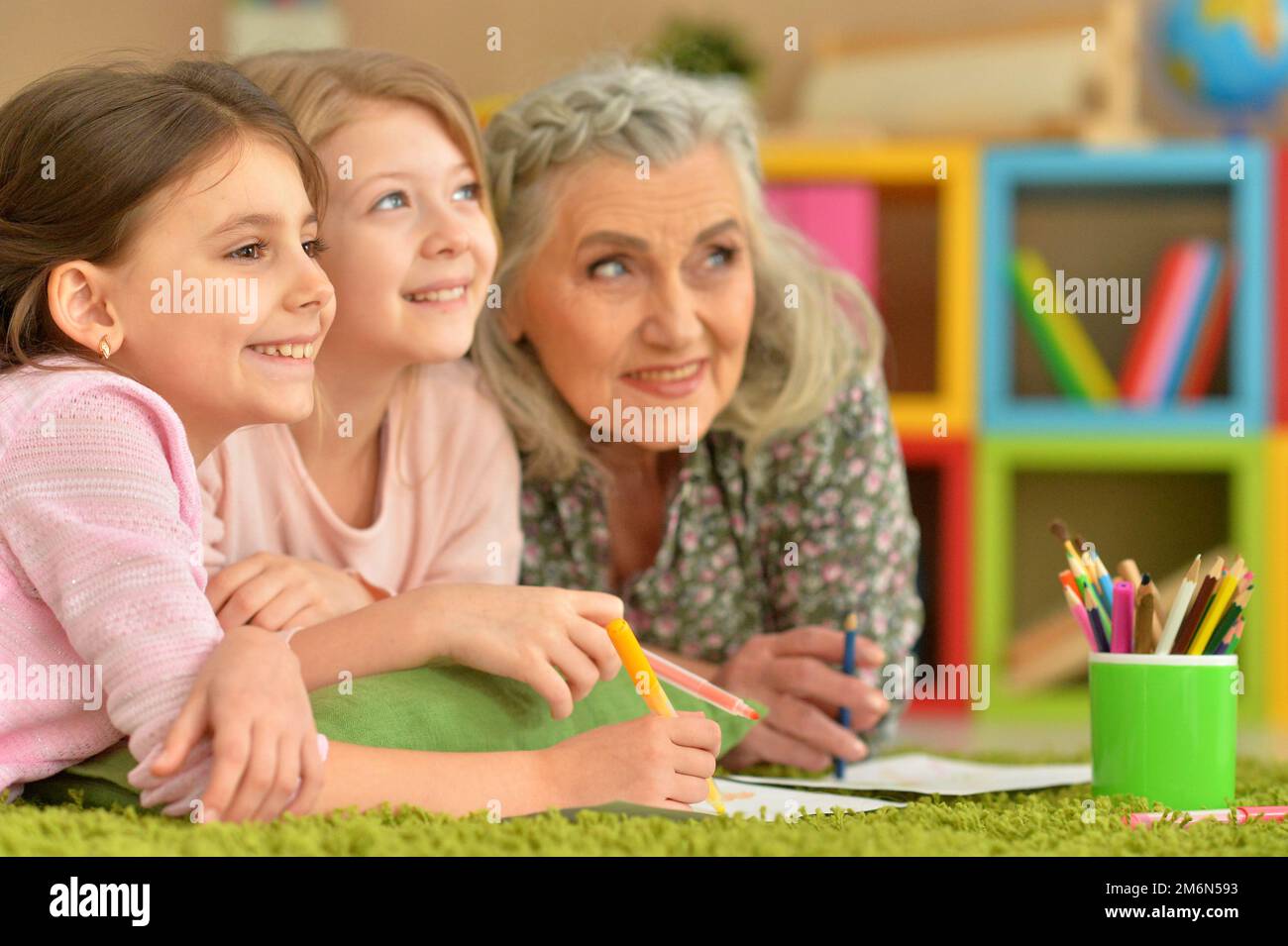 Großmutter und Enkelinnen machen Hausaufgaben zusammen zu Hause Stockfoto