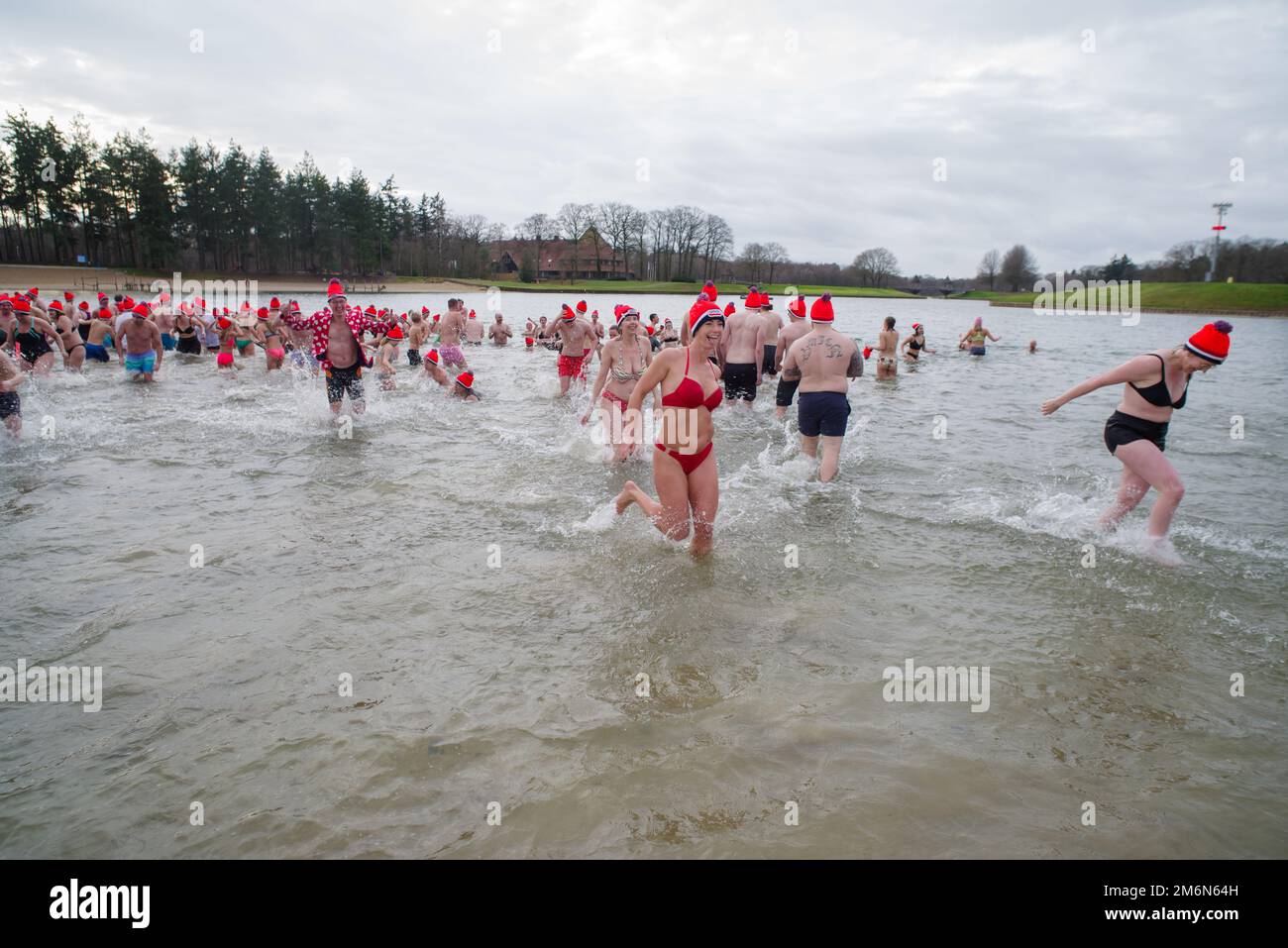 OLDENZAAL, NIEDERLANDE - 1. JANUAR 2023: Menschen, die beim traditionellen Neujahrsdiebstahl ins Wasser laufen Stockfoto