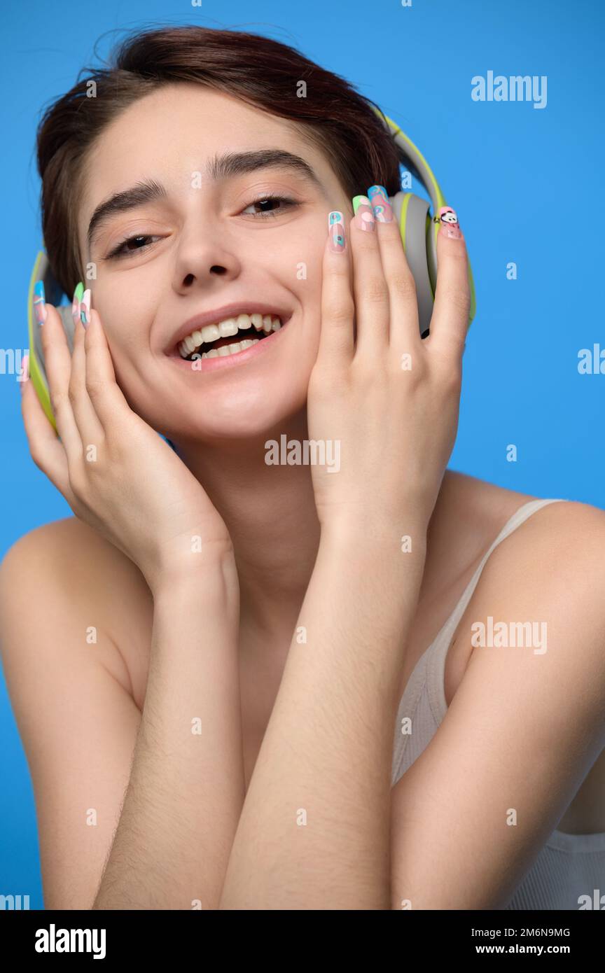 Süße junge Brünette, die Musik mit kabellosen bluetooth-Kopfhörern hört Stockfoto