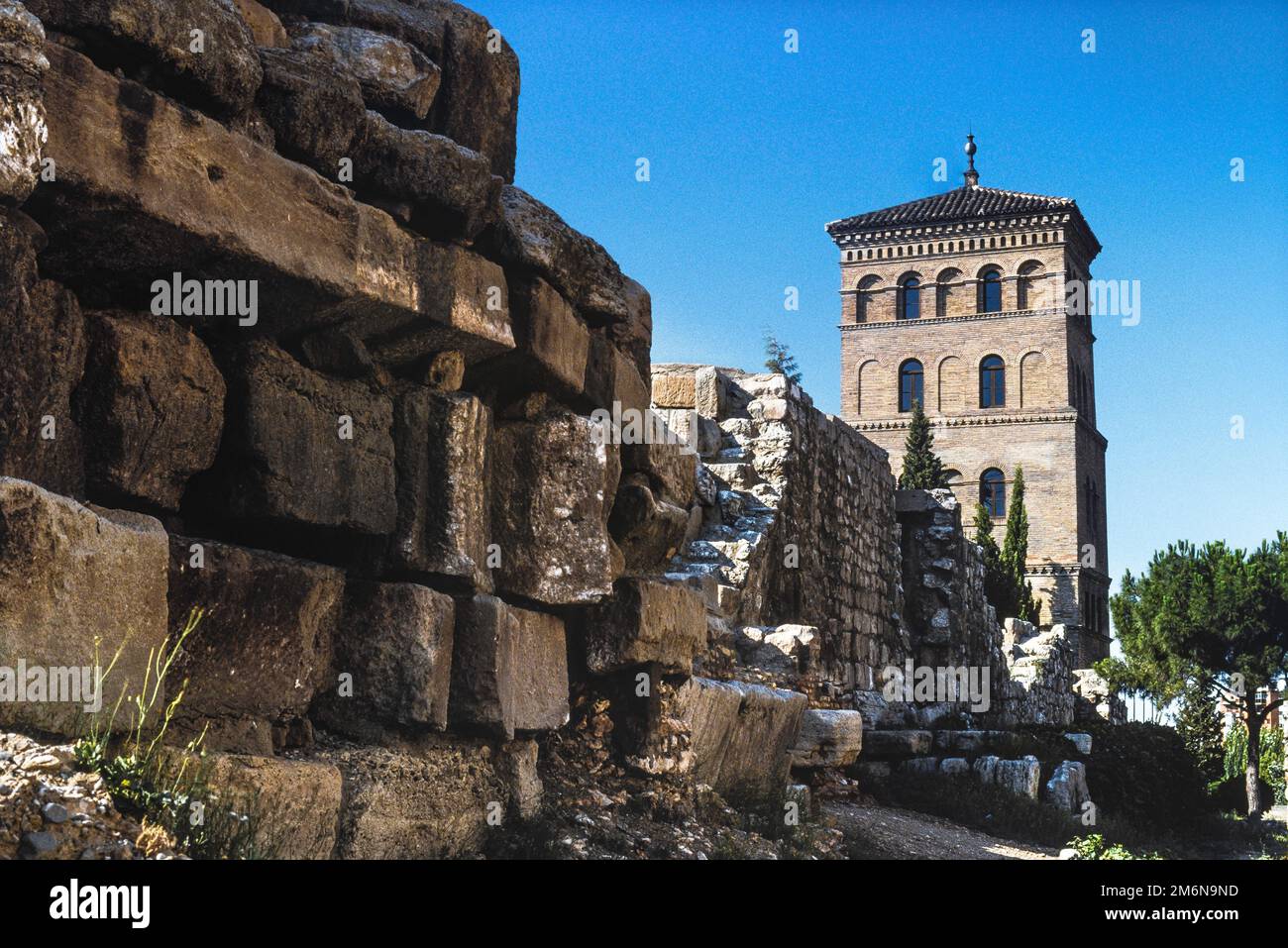 Römische Mauer Spanien, Blick im Sommer auf die Überreste eines Teils der römischen Mauer in Saragoza mit dem Zuda-Turm (Torreon de la Zuda) im Hintergrund. Stockfoto
